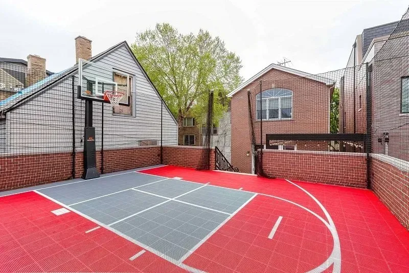There is a basketball court in the backyard of a house.