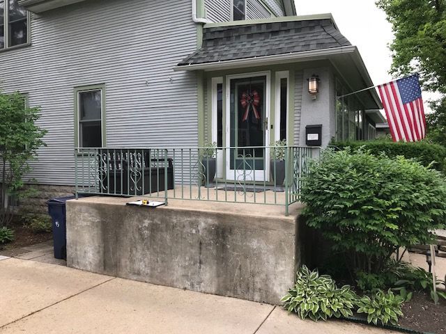 The front of a house with a porch and an american flag.
