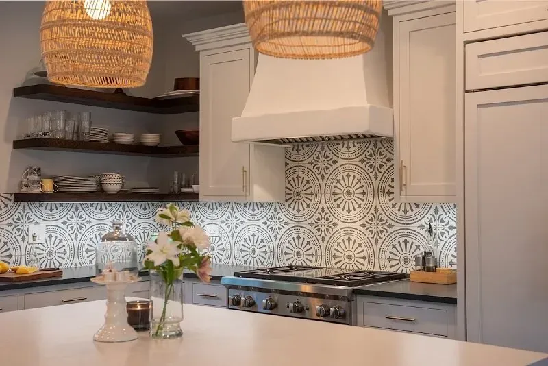 A kitchen with white cabinets , a stove , a refrigerator and a vase of flowers on the counter.