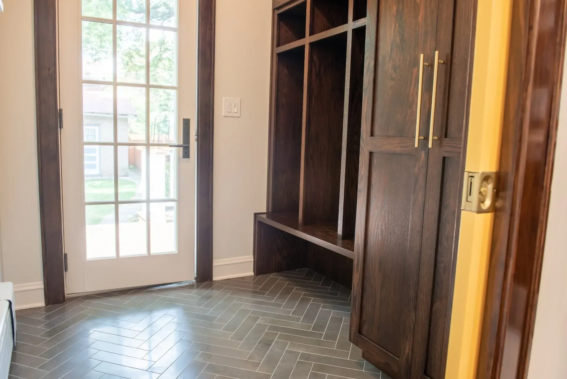A hallway with a sliding glass door and wooden cabinets.