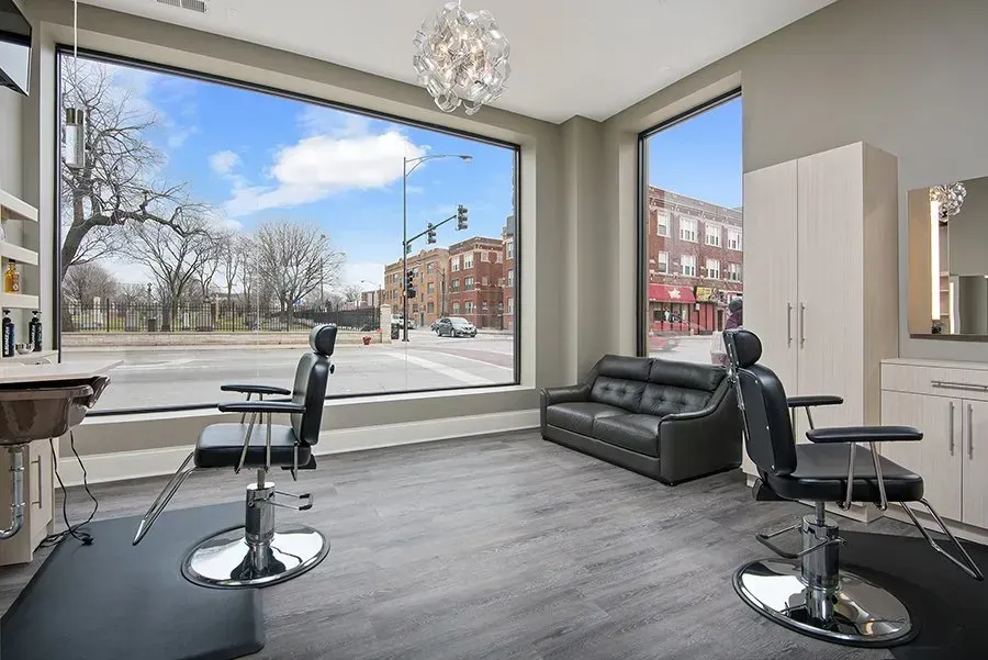 A salon with two chairs , a couch , and a large window.