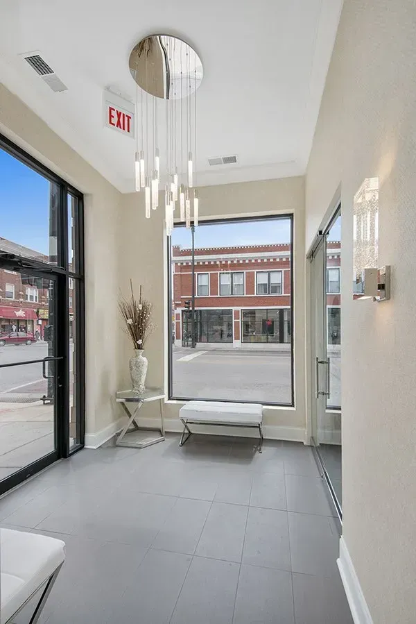 A hallway with a large window and a chandelier hanging from the ceiling.