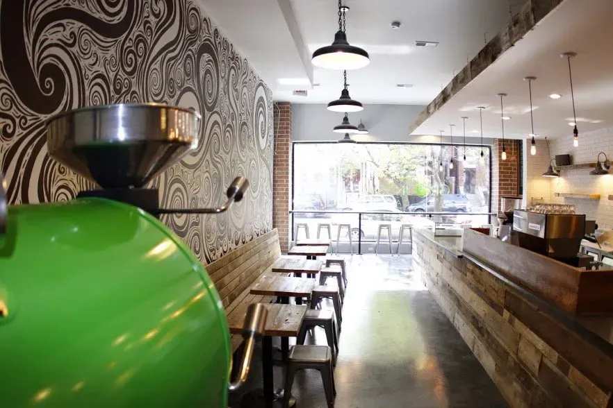 A green coffee grinder is in the middle of a restaurant.