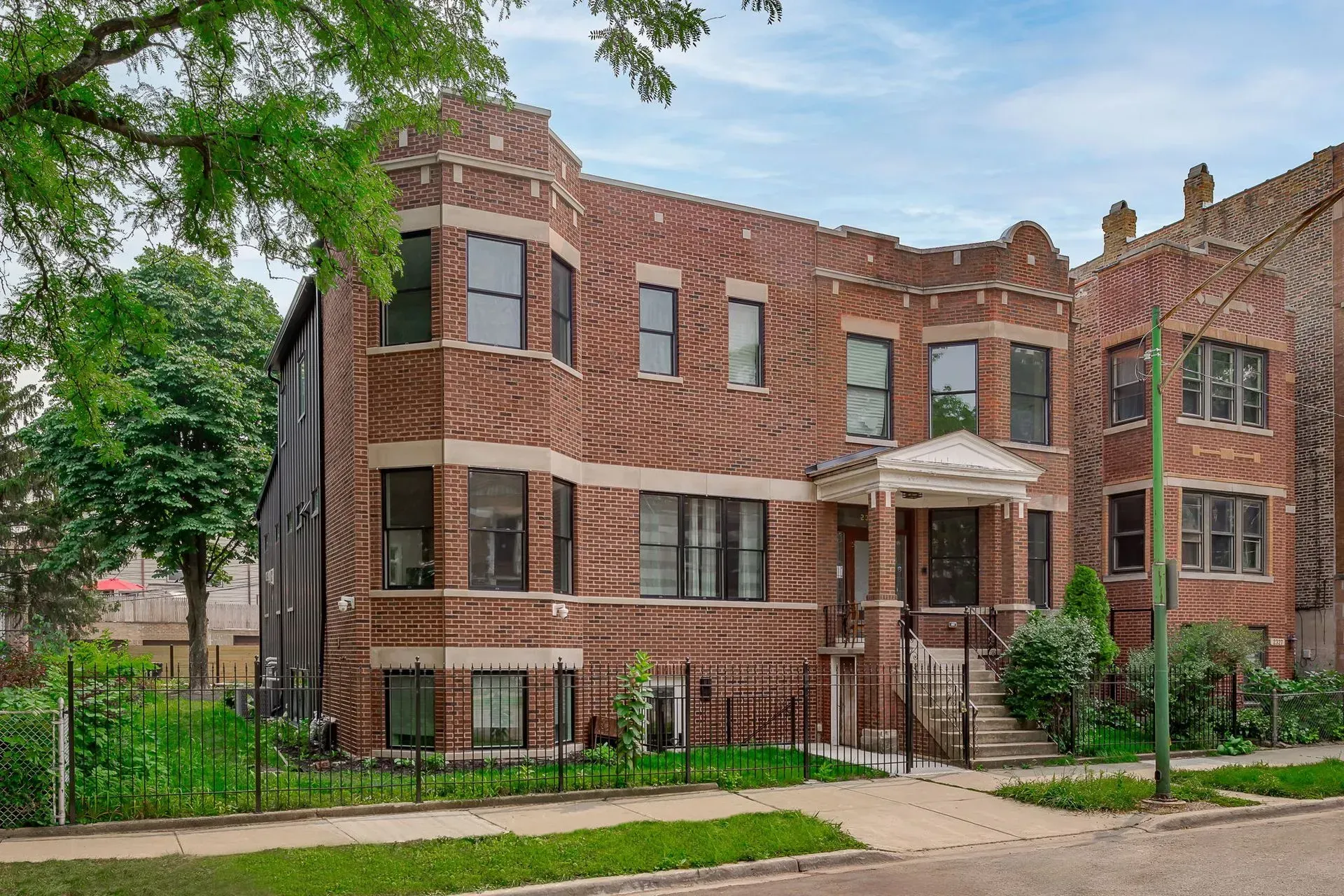 A large brick building with a lot of windows and a fence in front of it.