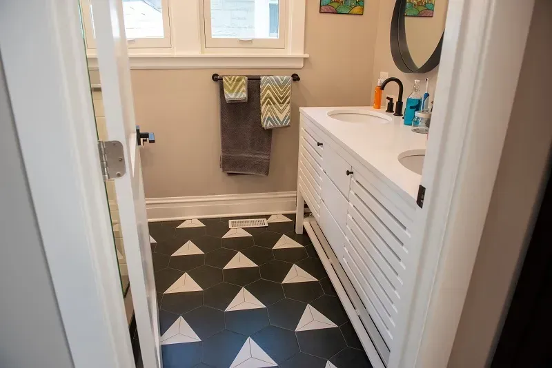 A bathroom with a black and white tile floor and a sink.