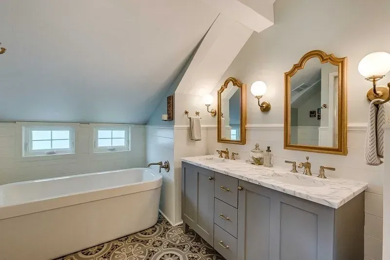 A bathroom with two sinks , a bathtub and two mirrors.
