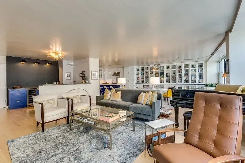 A living room with a couch , chairs , coffee table and piano.