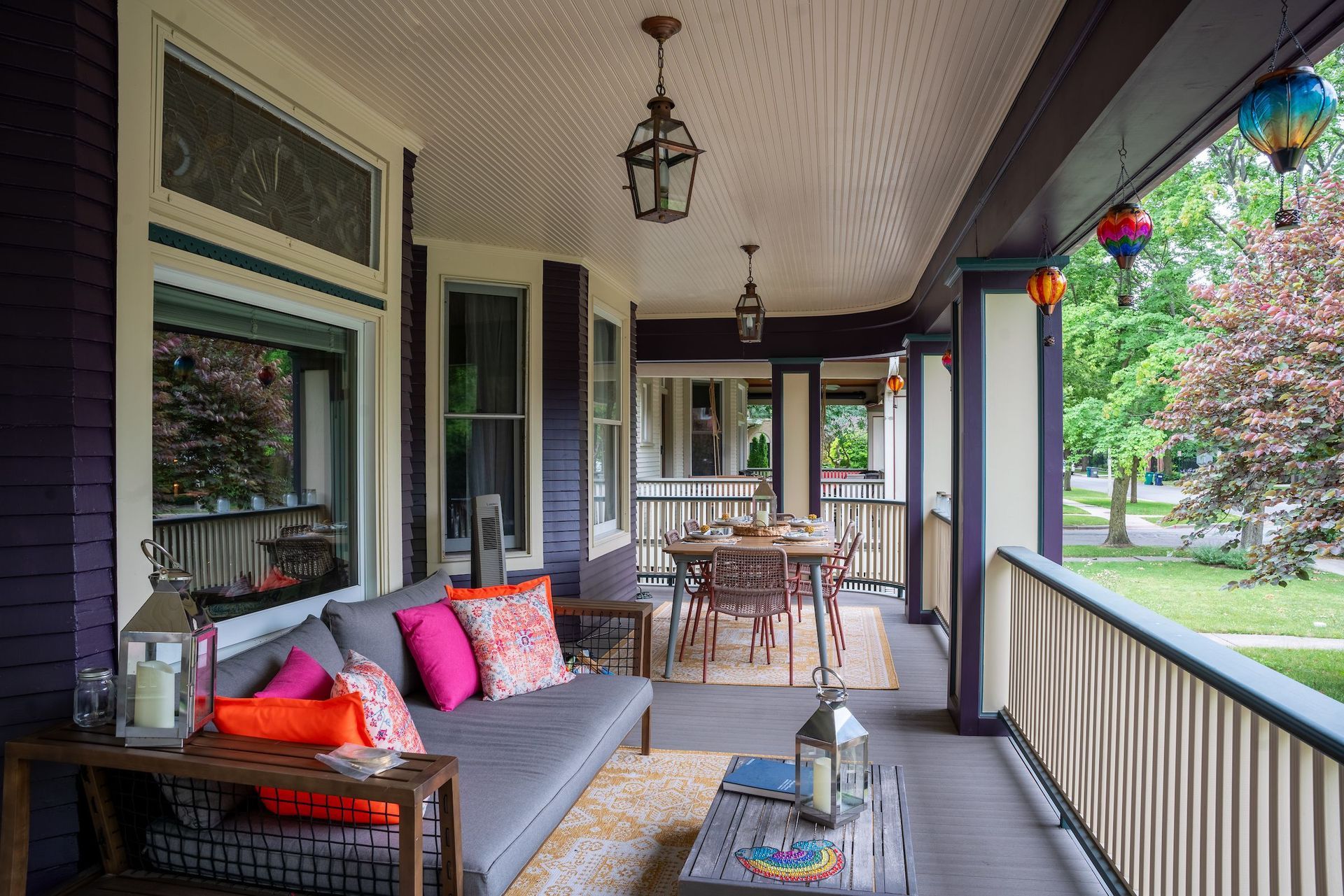 A porch with a couch , table and chairs on it.