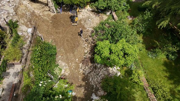 Aerial view of a dirt path through green trees and vegetation near a rocky area Aerial view of a dirt path through green trees and vegetation near a rocky area