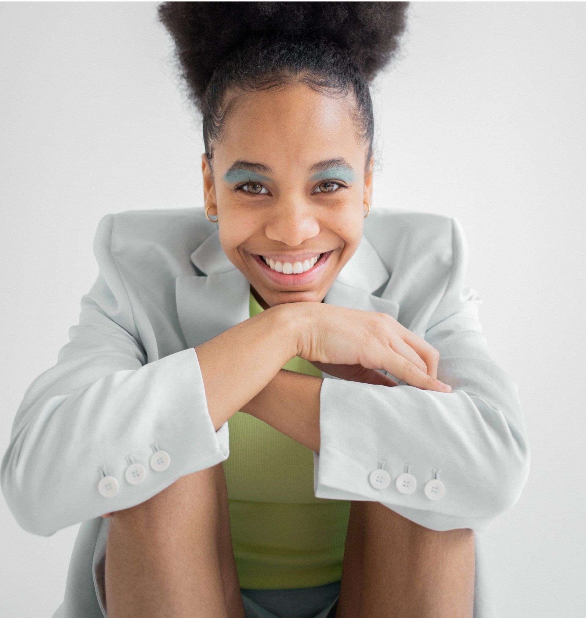 A woman is sitting on the floor wearing a white jacket and shorts