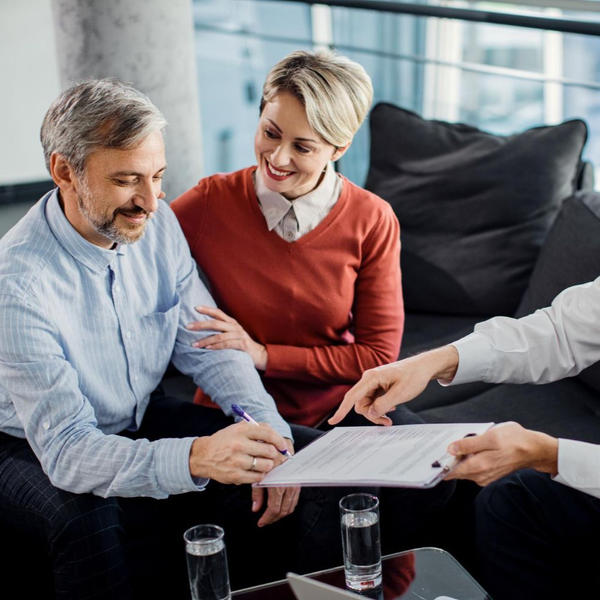 Couple signing document with advisor in modern office.