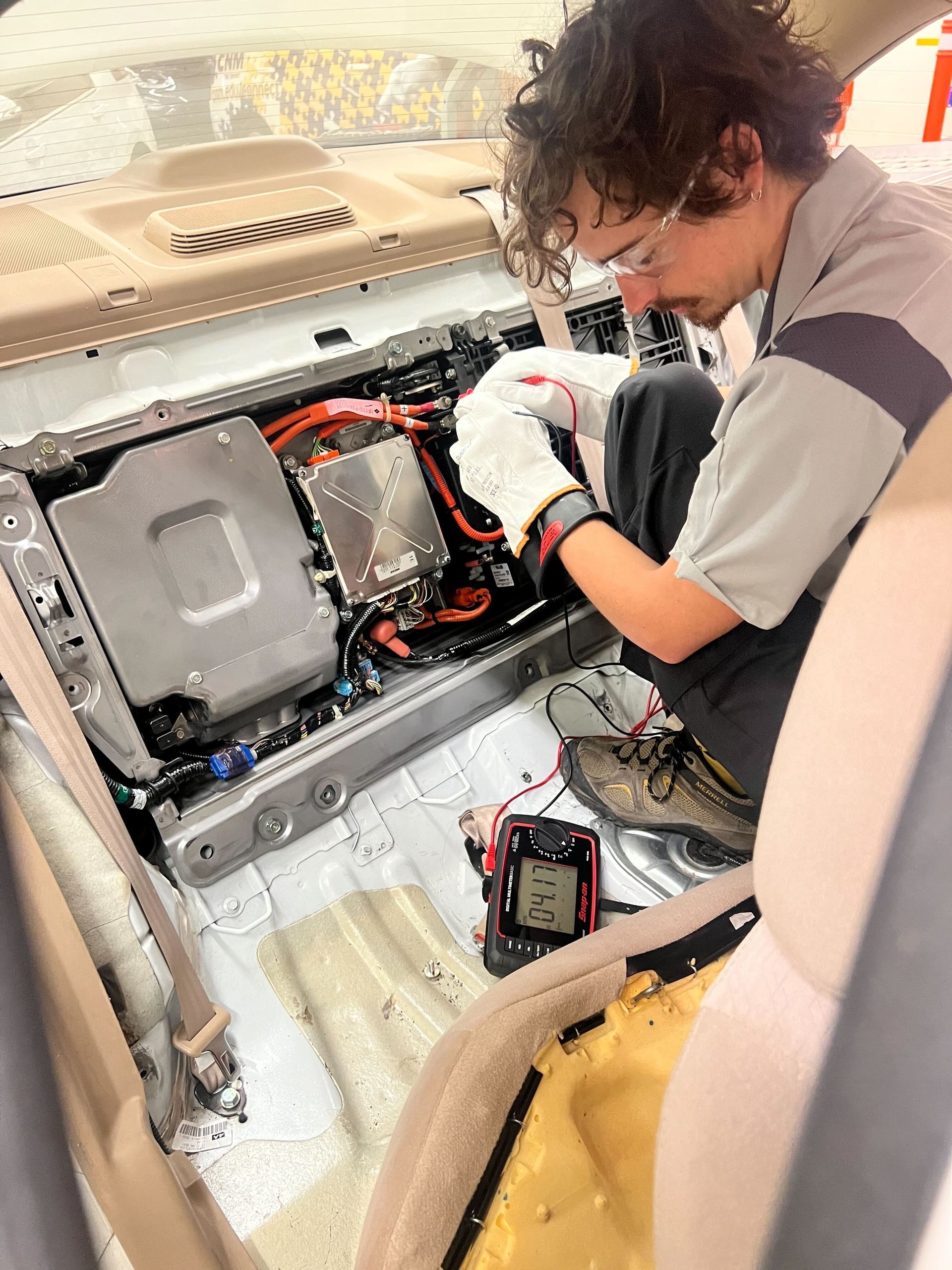 Technician Wearing Safety Glasses and Gloves Uses a Multimeter to Test Components of a Hybrid Car's Battery | Mango Automotive