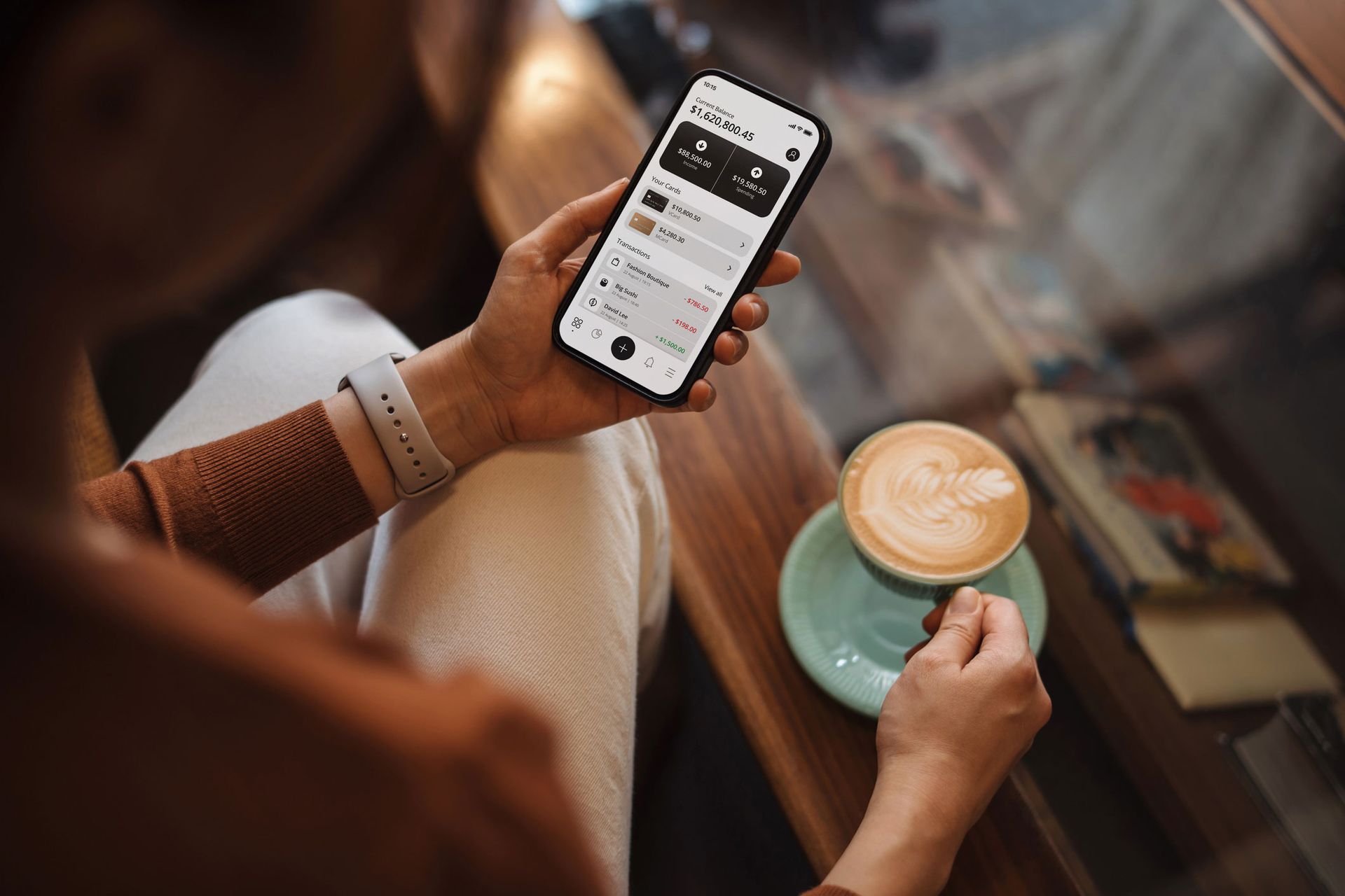 A woman is sitting at a table with a cup of coffee and a cell phone.