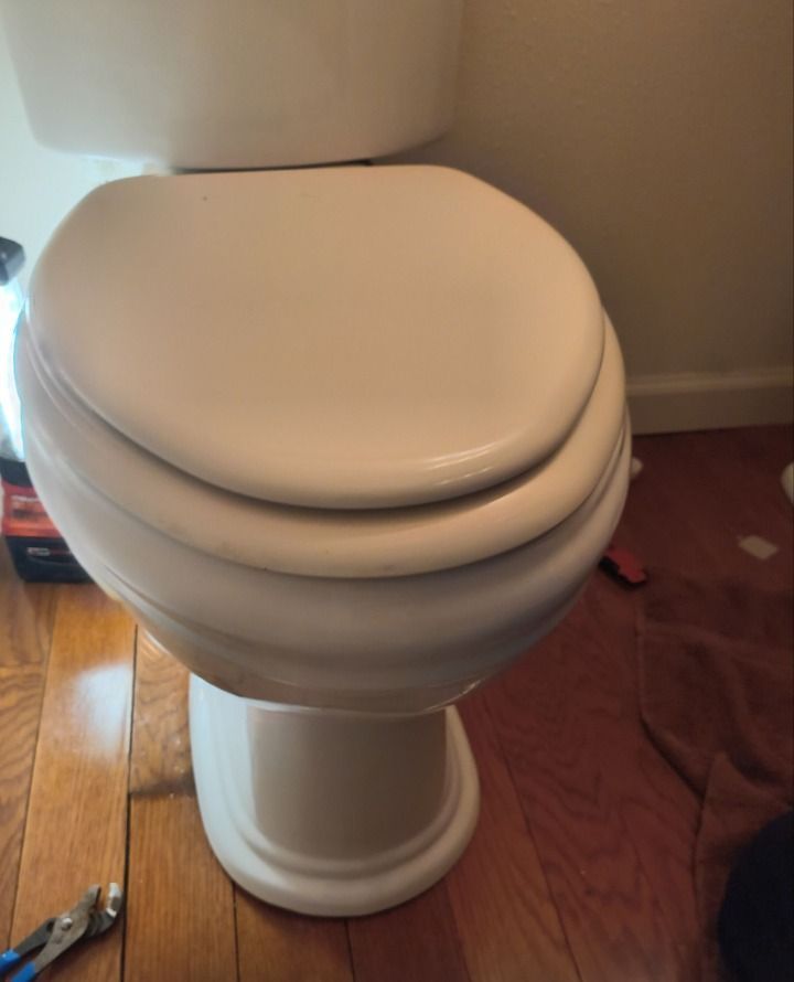 White toilet with closed lid in a bathroom, viewed from the side.