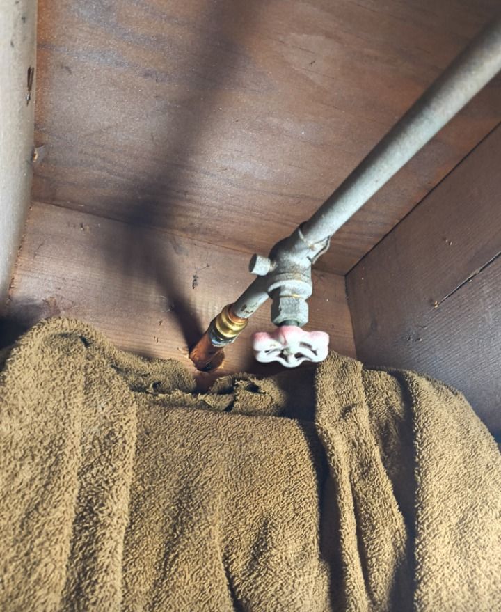 Water pipe with shutoff valve above a brown towel-covered surface