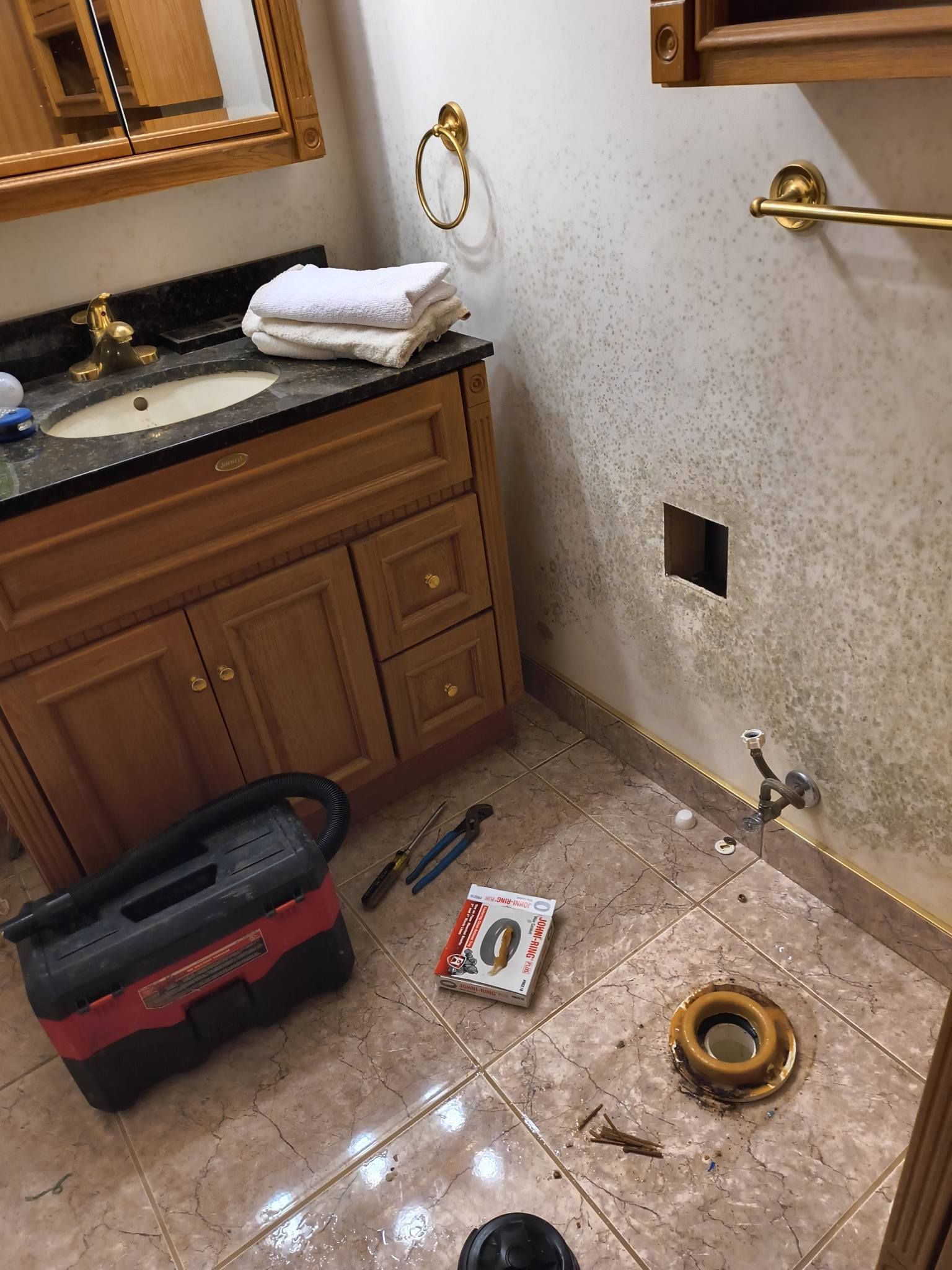 Bathroom under renovation with vanity, tools, and exposed plumbing on the floor