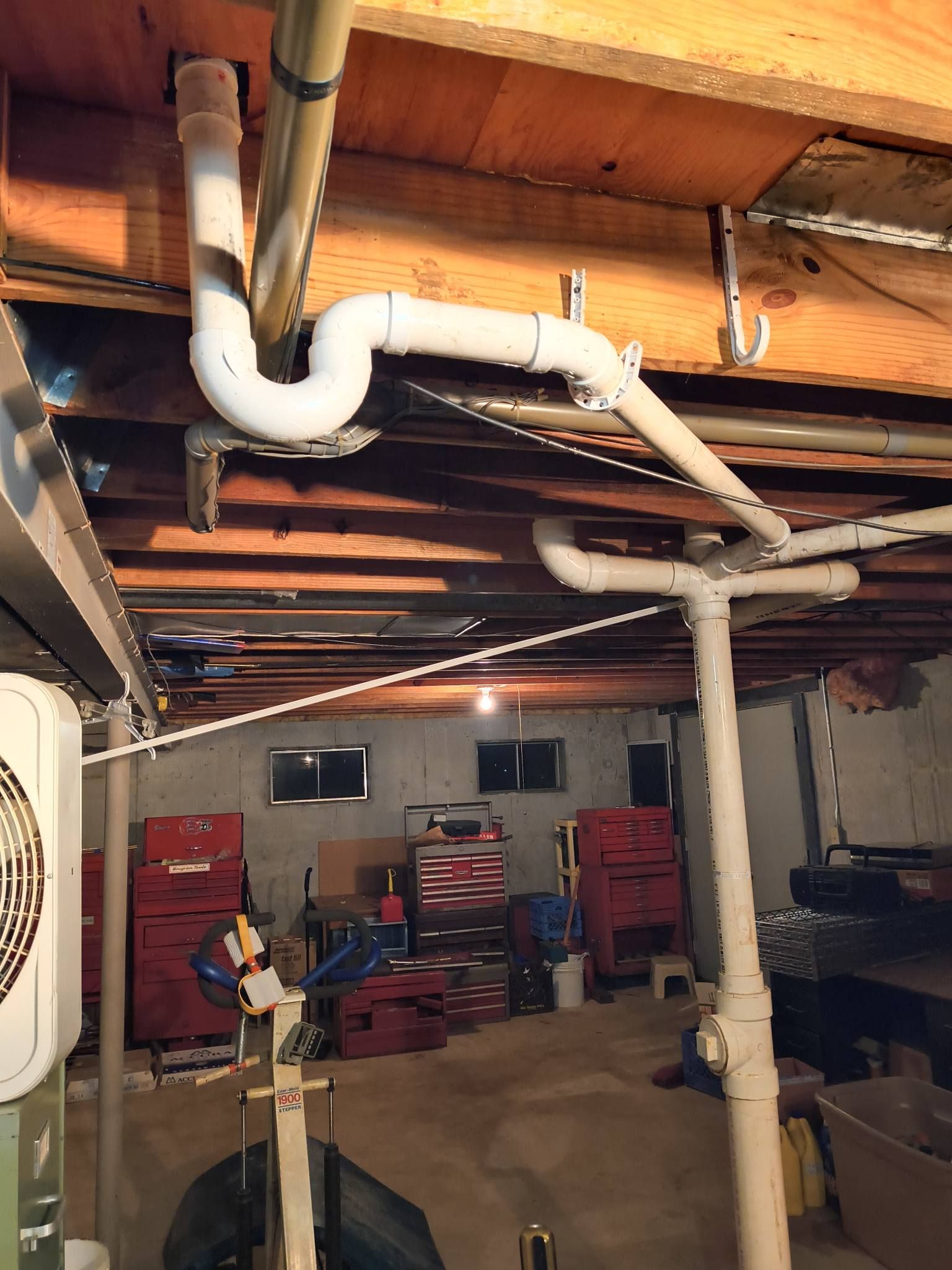 Basement utility room with exposed pipes, wood beams, and stacked red bins.