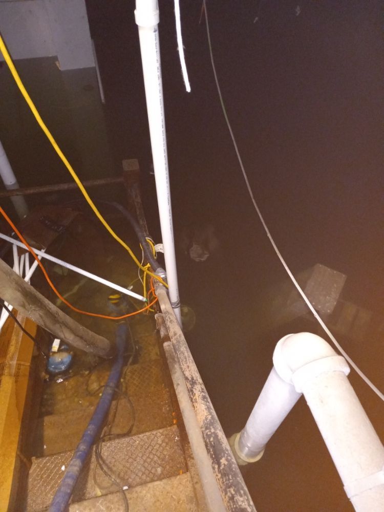Dark industrial stairwell with pipes, cables, and metal steps in a dim utility space