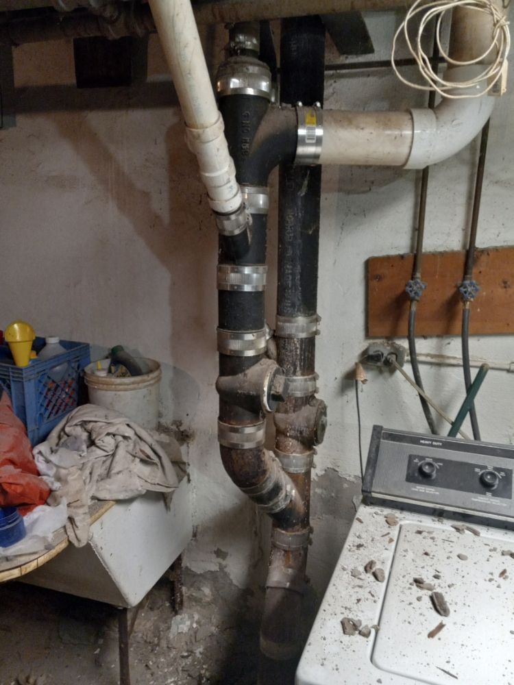 Basement utility area with exposed pipes, a sink, and a washing machine next to a cinder block wall.