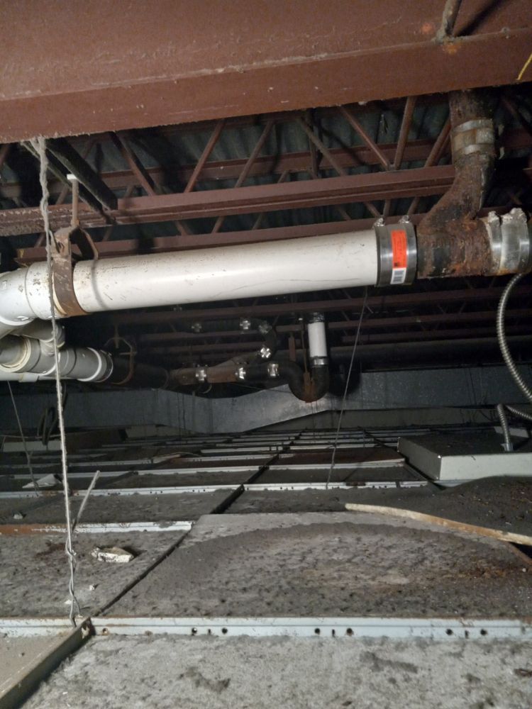 Exposed pipes and ducts under a floor in a crawlspace or basement ceiling