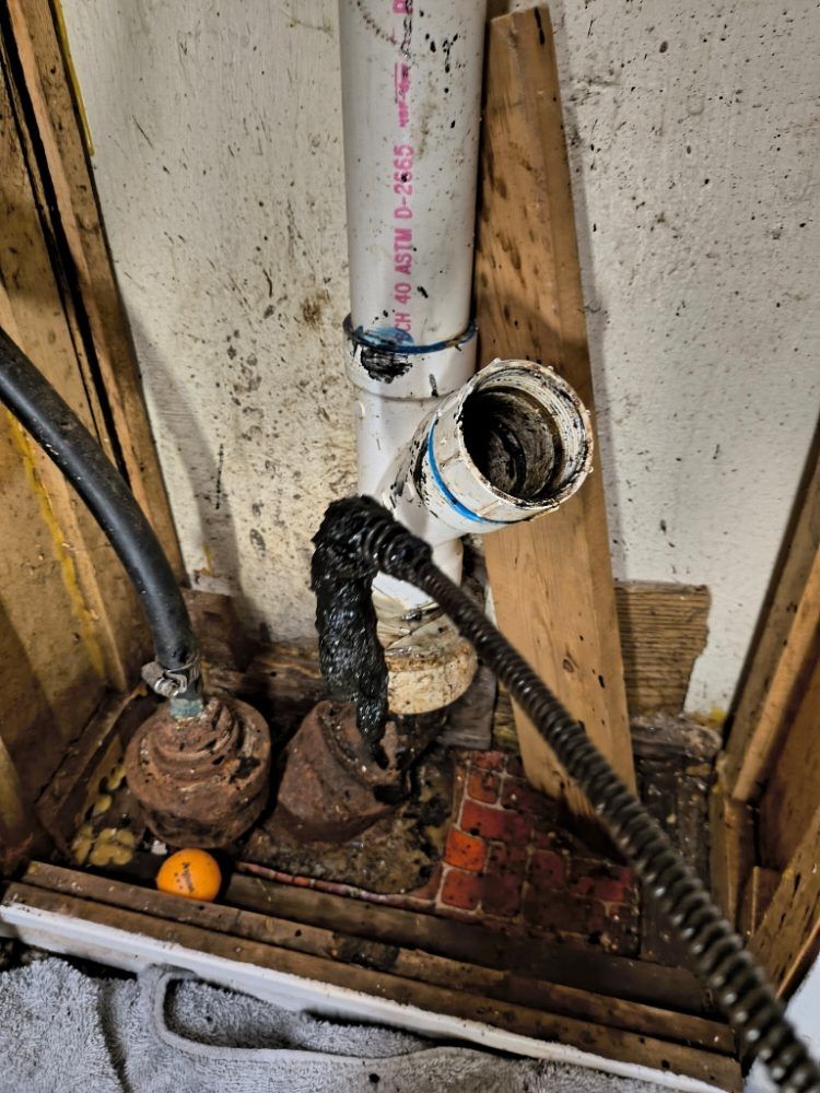 Corroded exposed plumbing pipes and valves in a utility wall compartment with dirt and debris