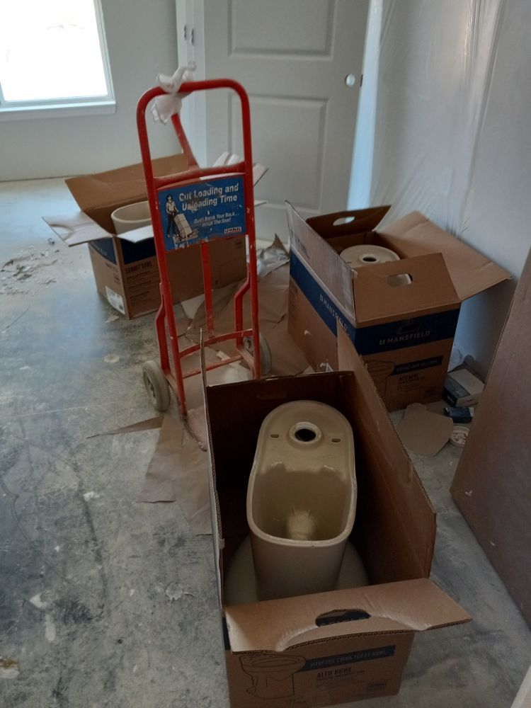 Boxes and a red dolly in an empty room, with a beige appliance in the foreground.