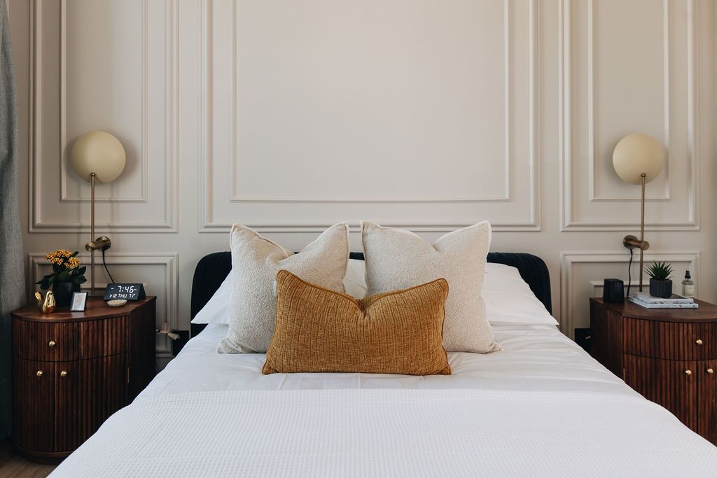 Bedroom with a bed, nightstands, lamps, and decorative wall molding. Purple Martin Hotel