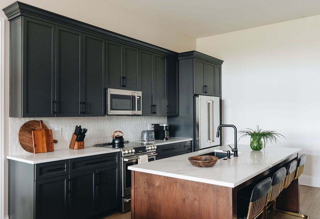 Modern kitchen with dark cabinets, white countertops, island with seating, stainless steel appliances. Purple Martin Hotel
