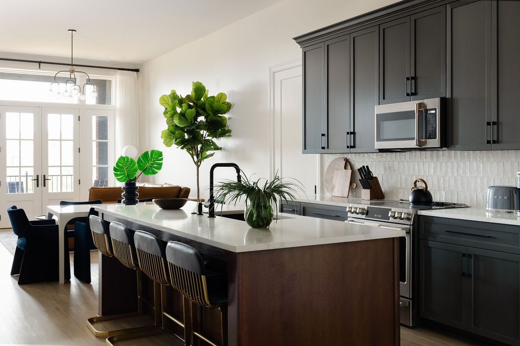 Modern kitchen with dark cabinetry, large island with seating, and white walls. Purple Martin Hotel