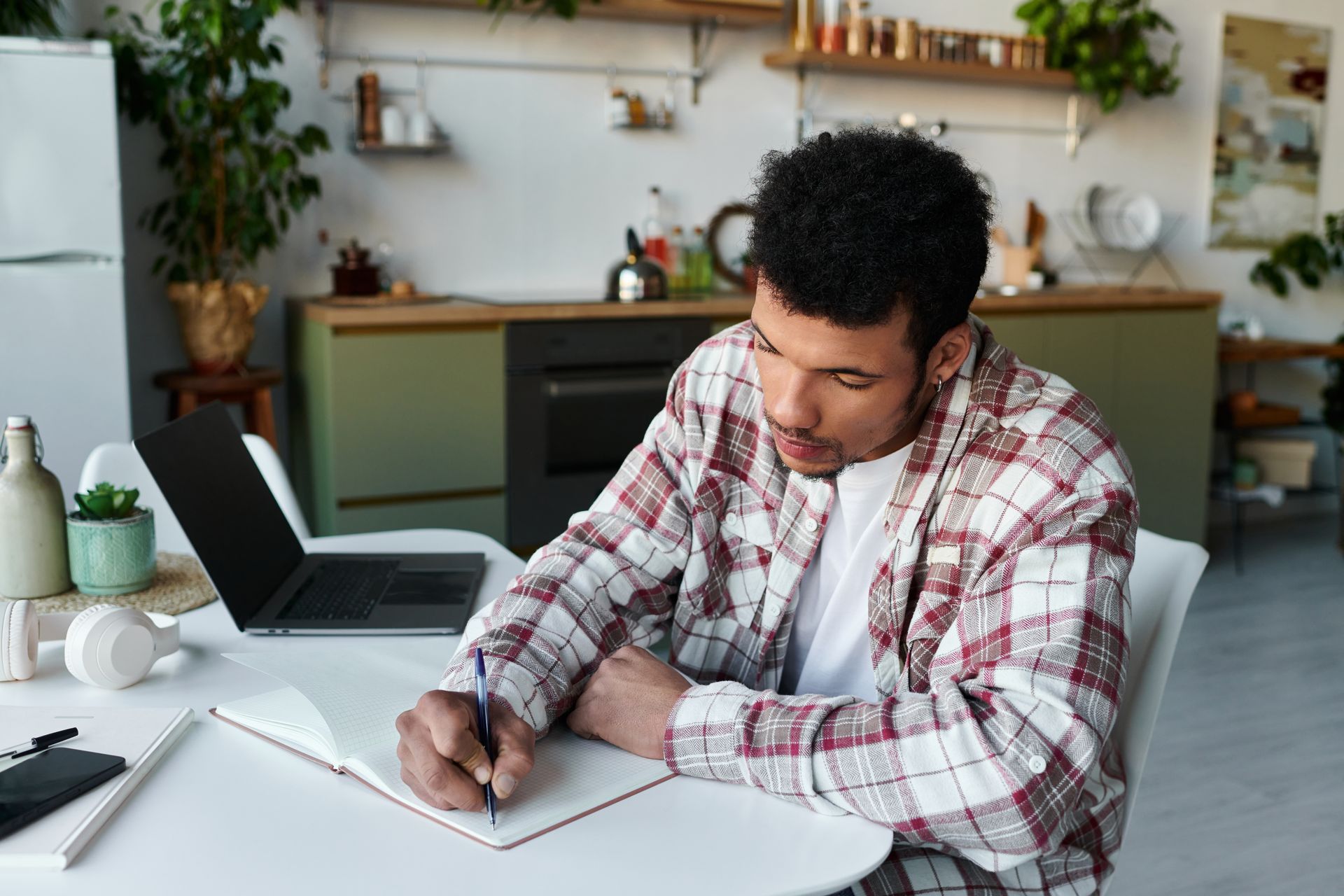 Person on a video call at a desk with a laptop, lamp, and coffee mug in a small home office.