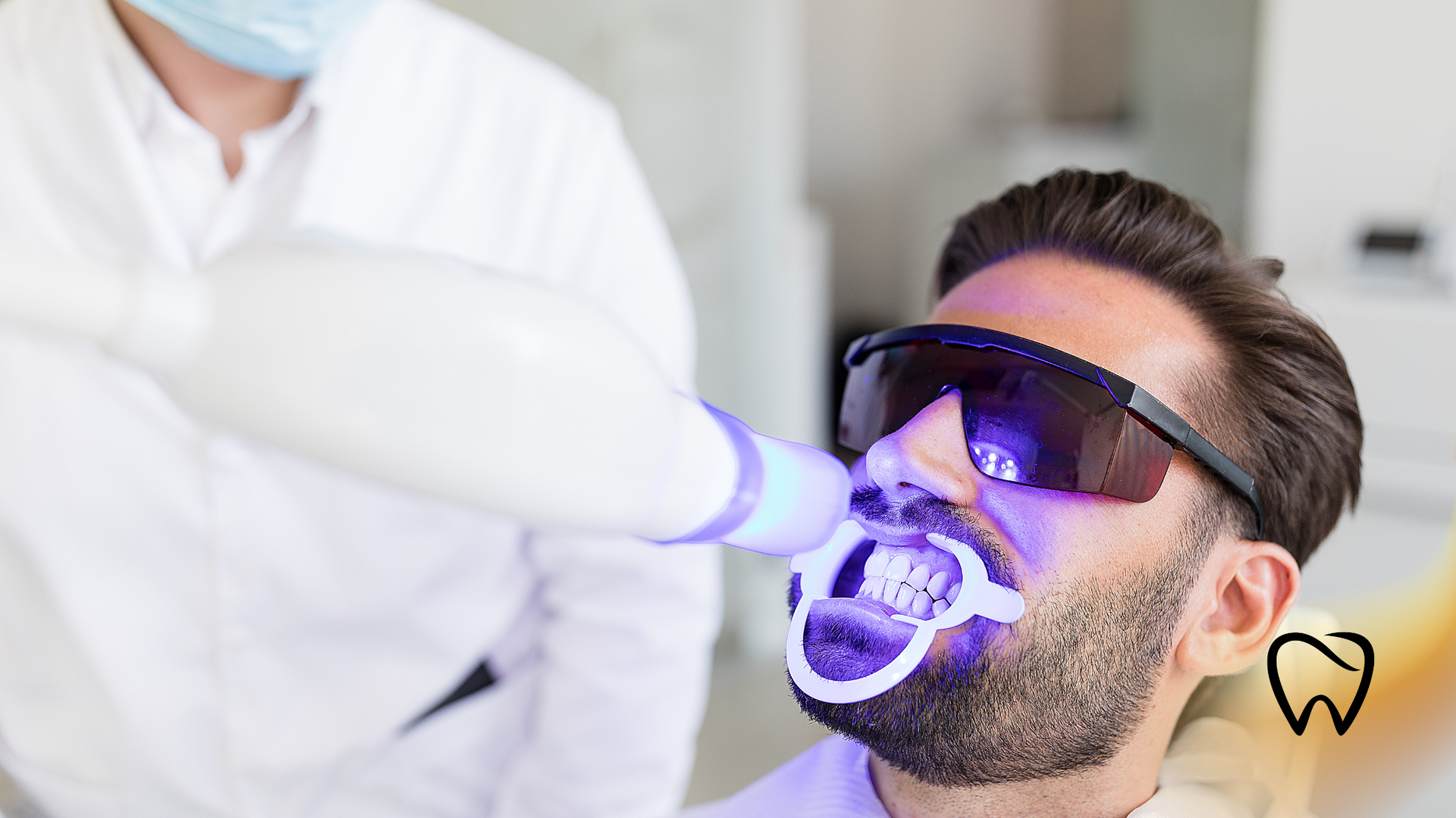 Man undergoing teeth whitening with UV light at a dental clinic.