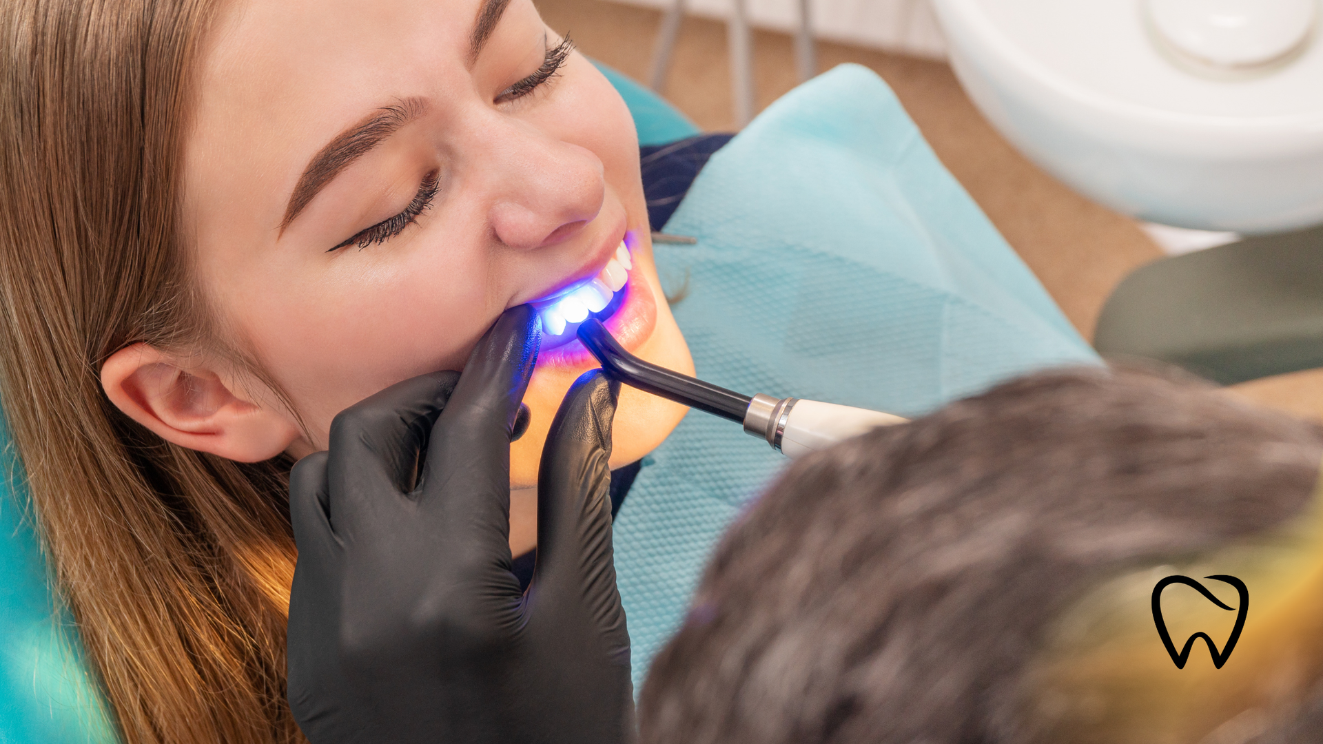 Dentist using a blue curing light on a patient’s teeth during treatment