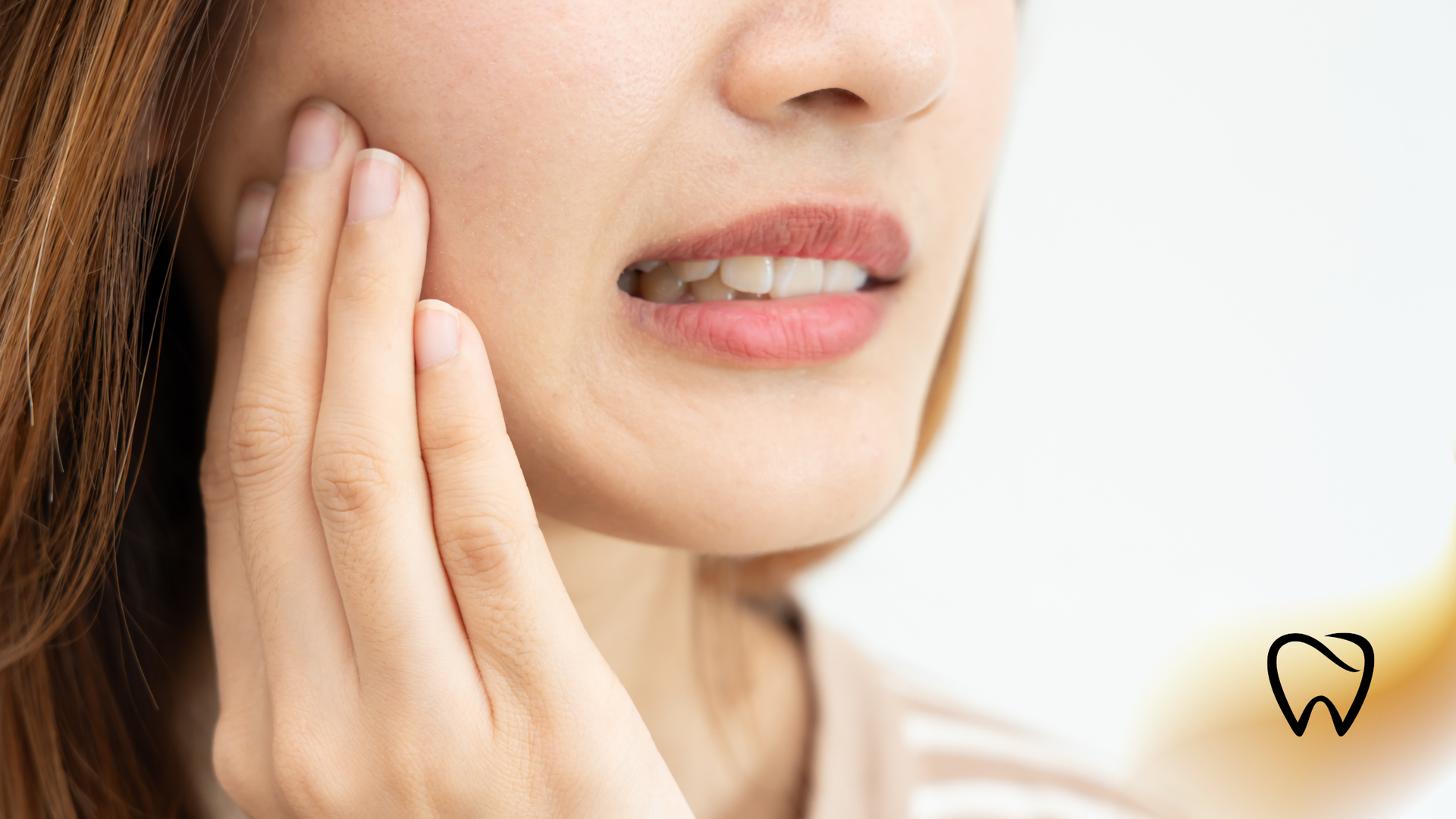 Woman with hand on cheek, showing discomfort, possibly due to toothache.
