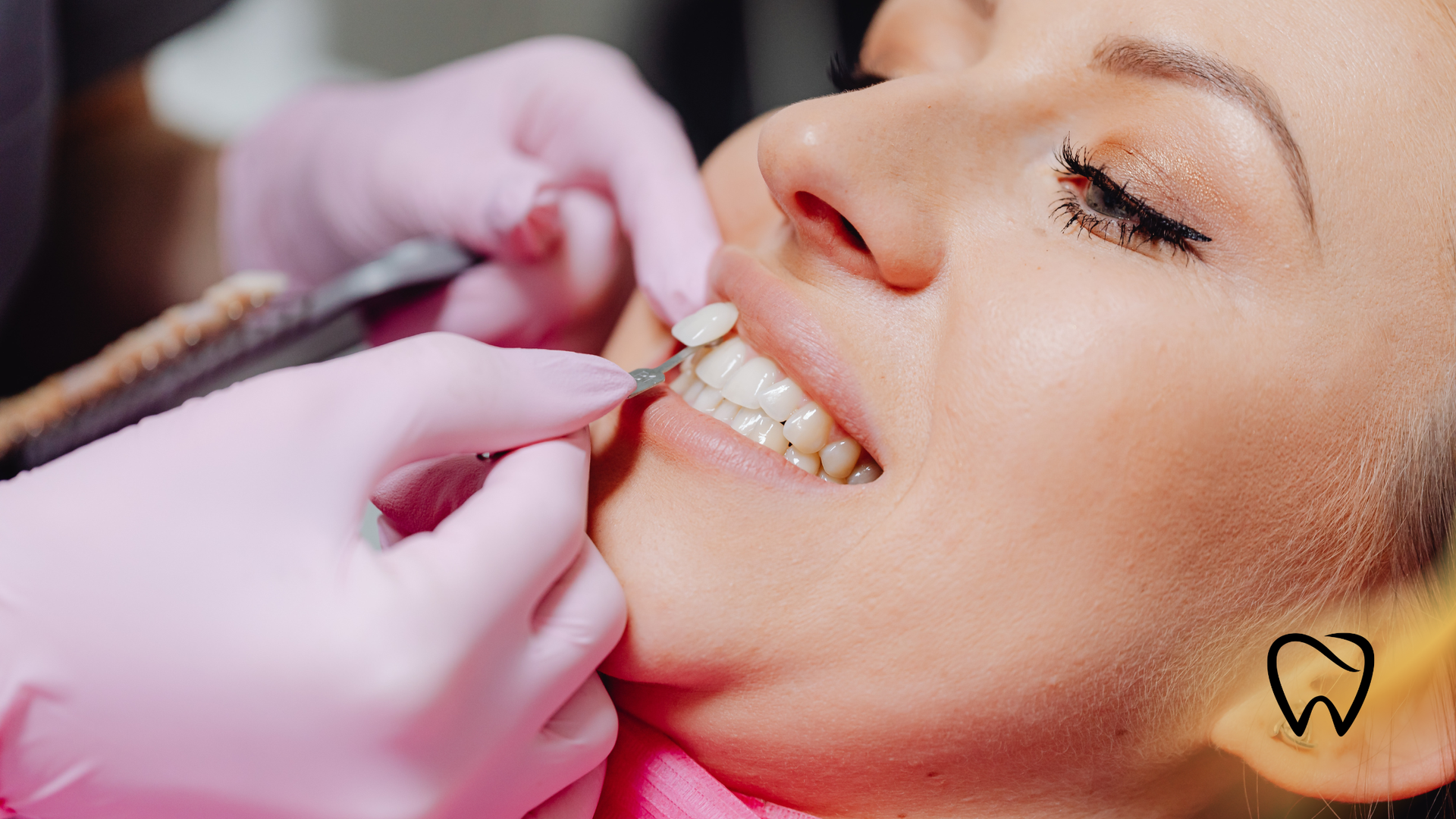 Dentist examining a smiling patient’s teeth with gloved hands and dental tools