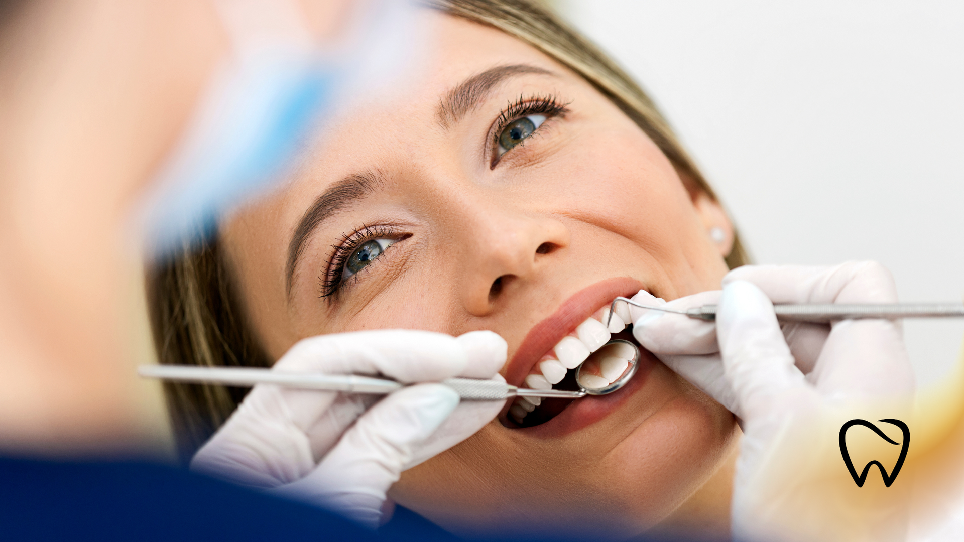 Woman at a dentist appointment, smiling with mouth open, dental tools in use.