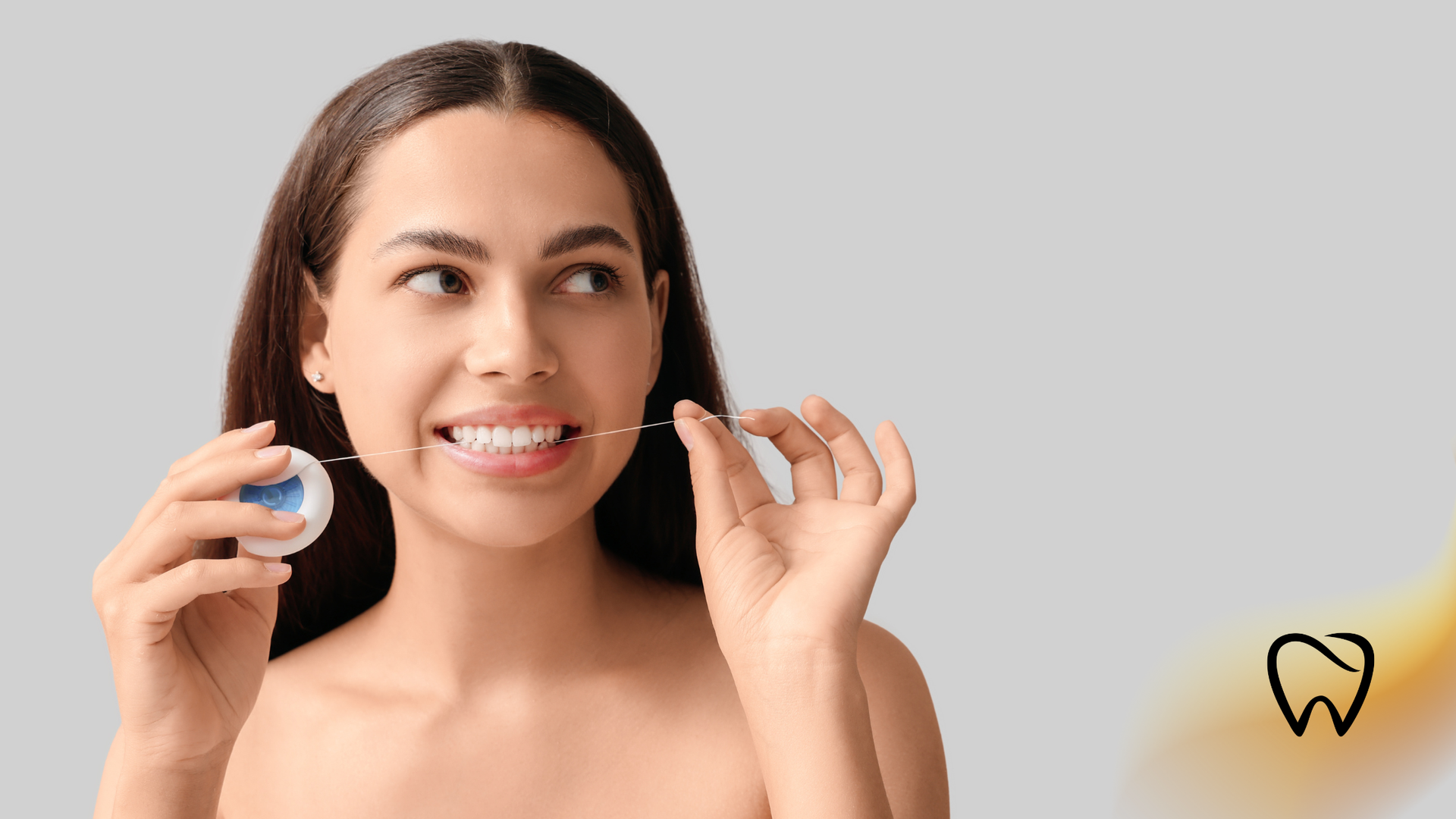Smiling person holding dental floss and a floss container against a light background