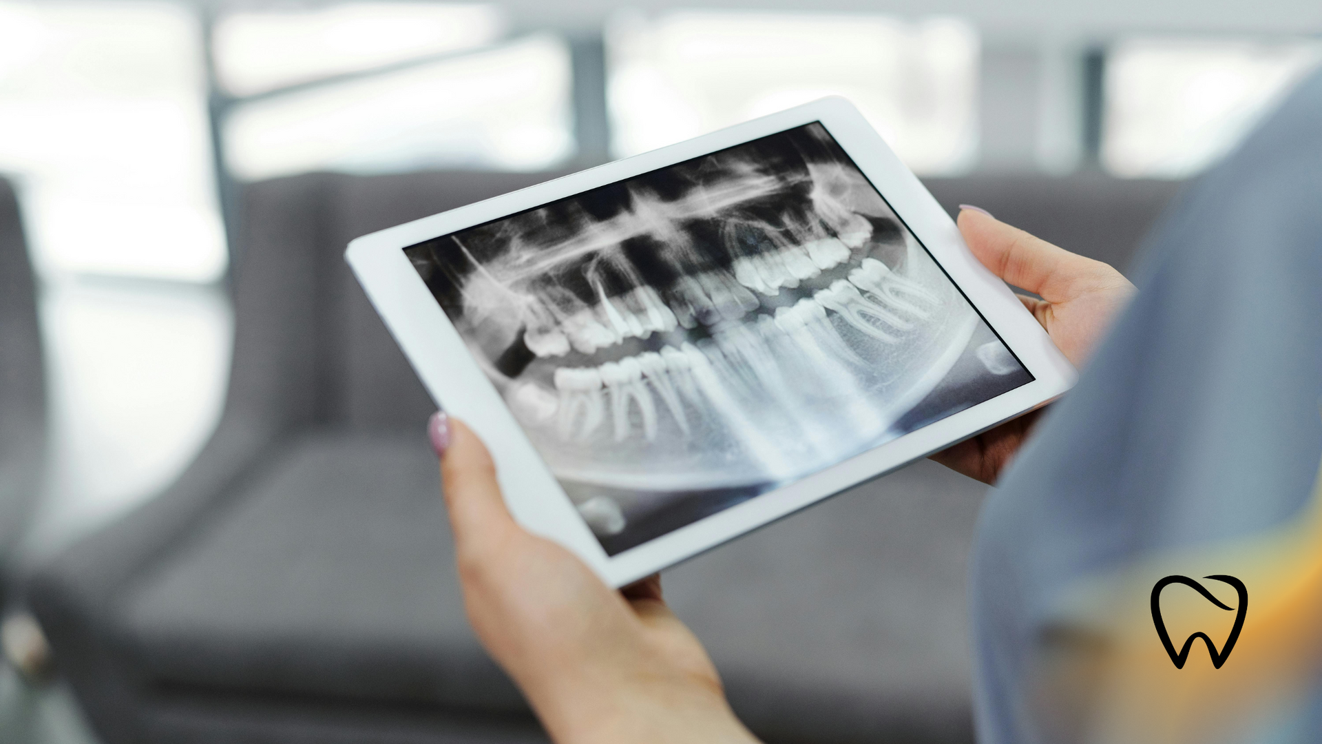 Person holding a tablet displaying a dental x-ray in a waiting room.