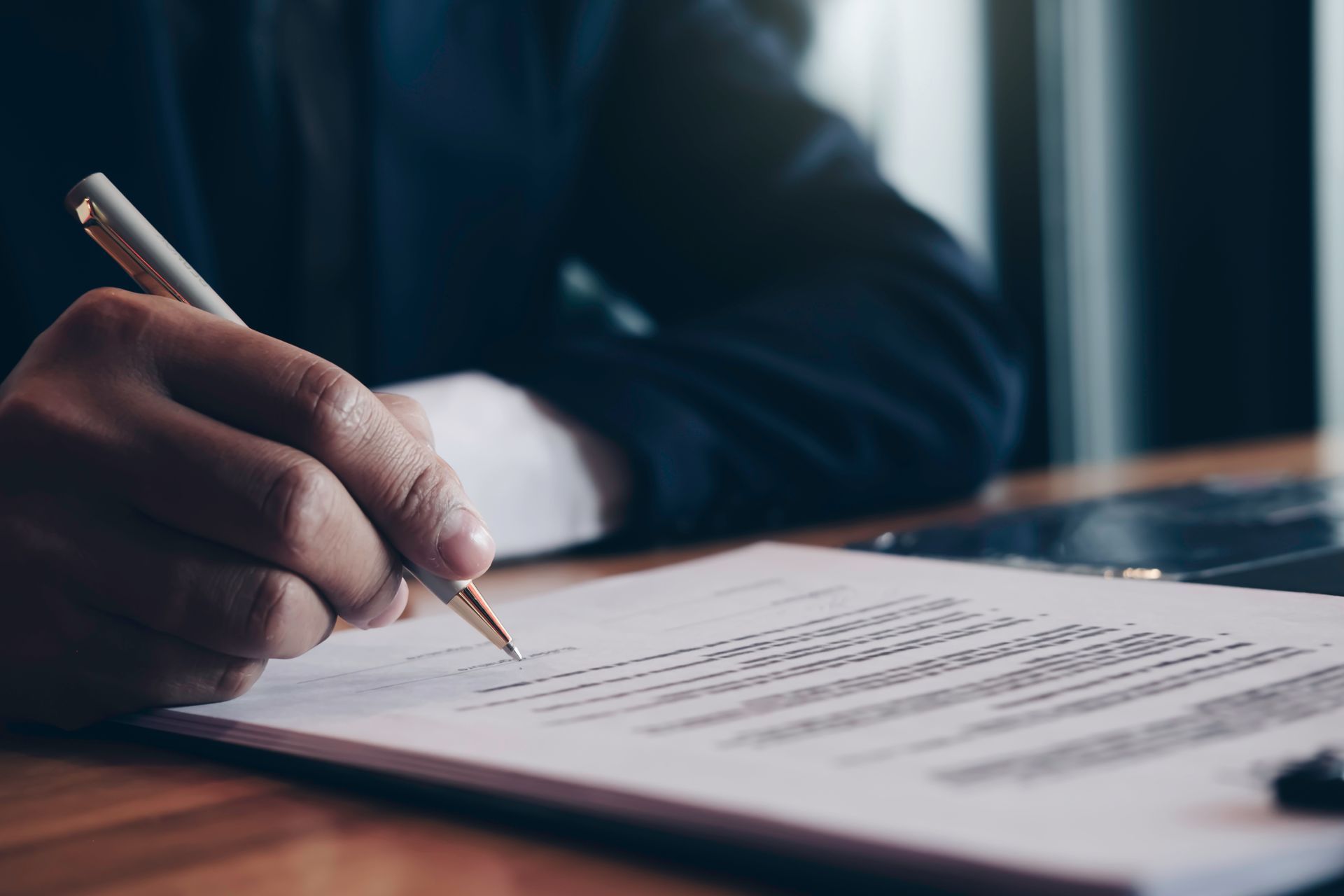 Hand writing notes on a document at a desk with a pen Hand writing notes on a document at a desk with a pen