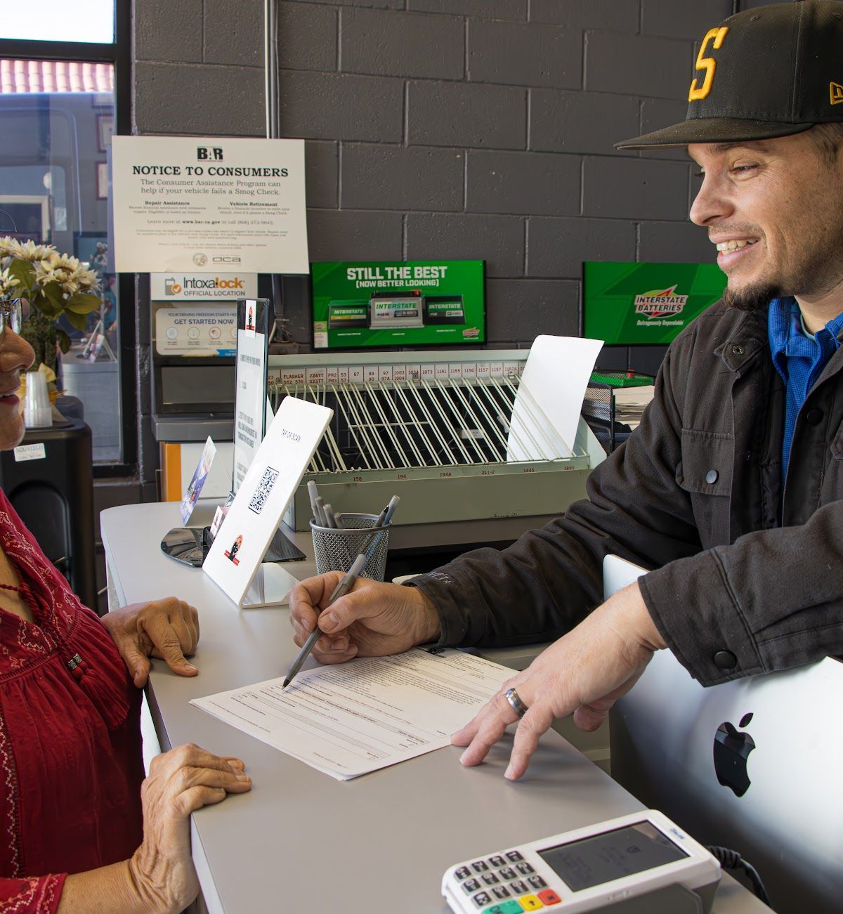 Customer signing a form at a store counter | O.C. Automotive and Diagnostics