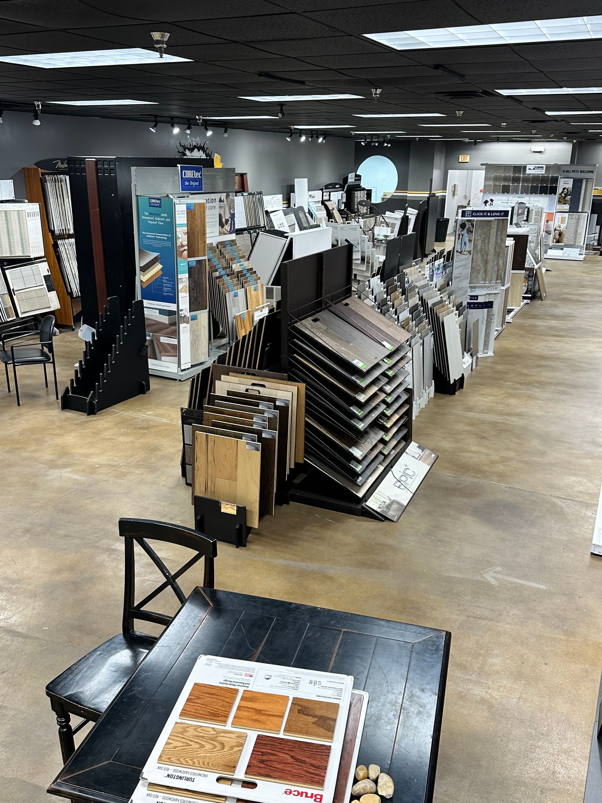 Interior of a tile showroom with display racks, samples, and a table in the foreground