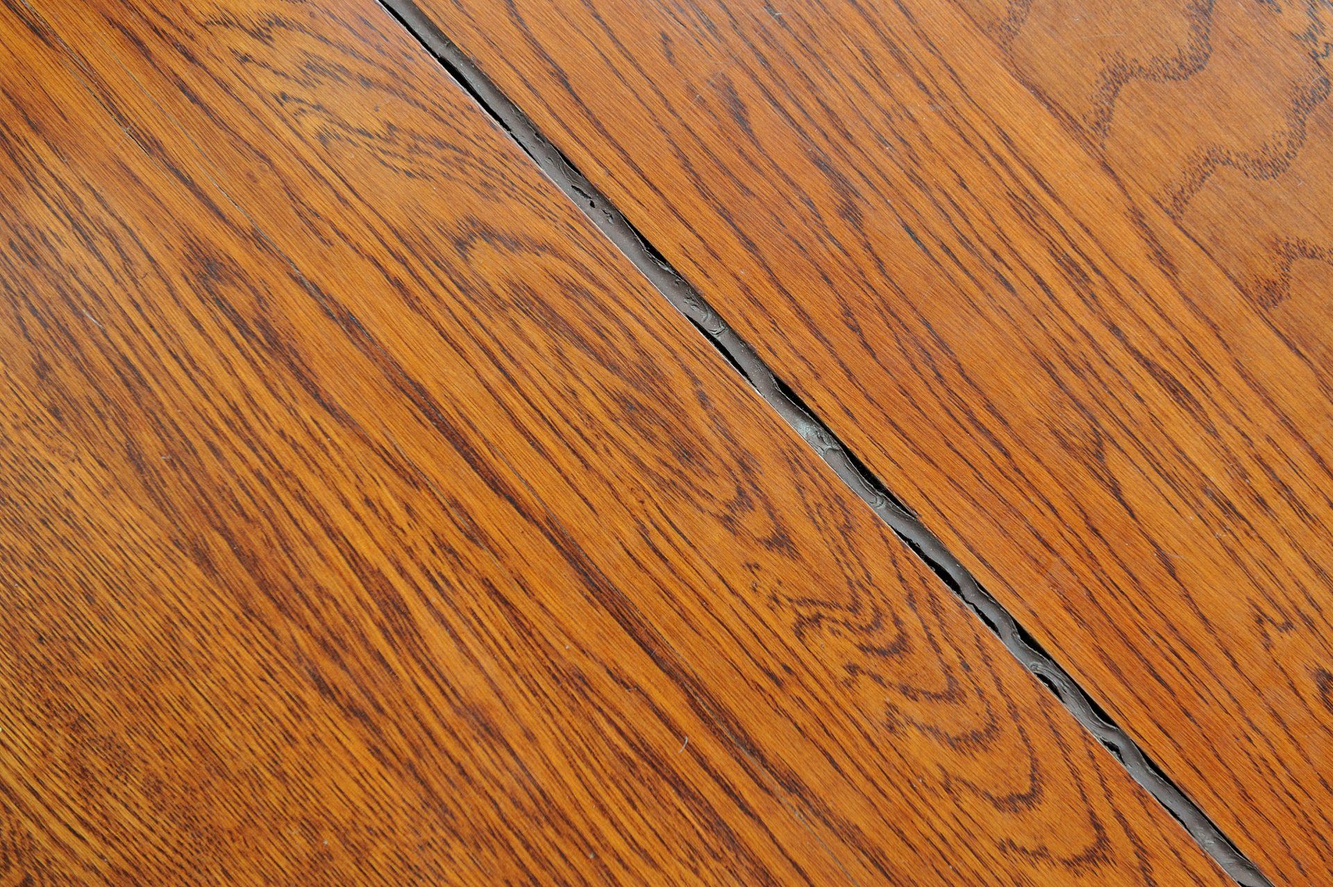 Close-up of orange-brown wooden floorboards with a dark diagonal seam