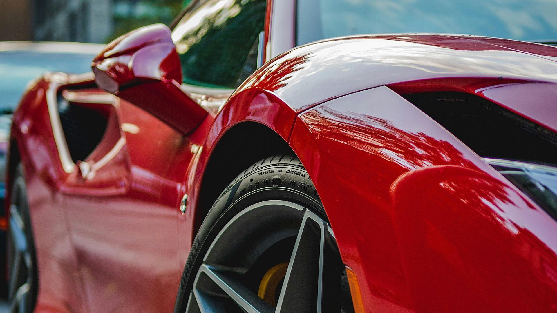 Close-up of a red sports car’s front fender and wheel on a road