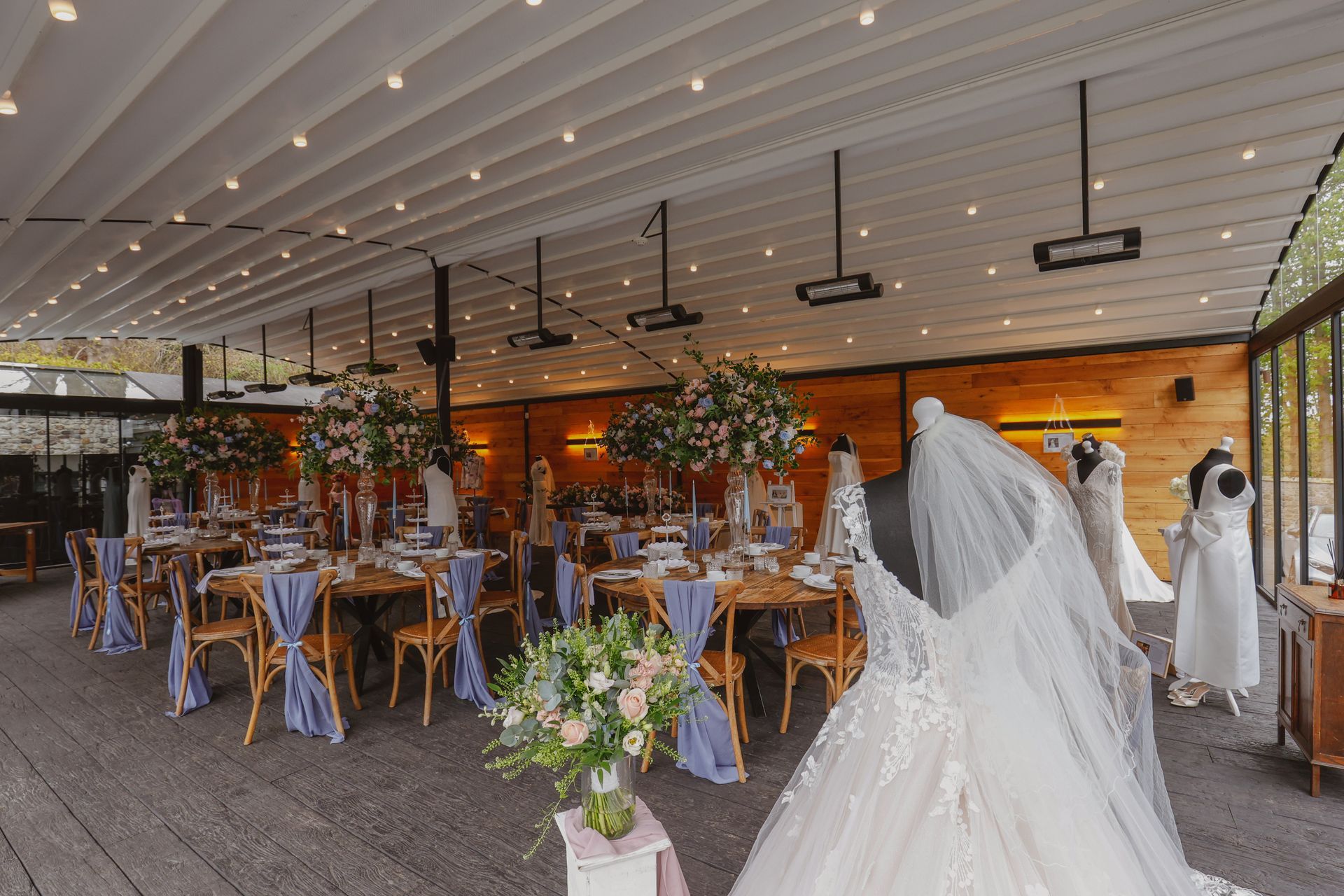 Wedding reception venue with decorated tables, string lights, and a bride in a white gown and veil.