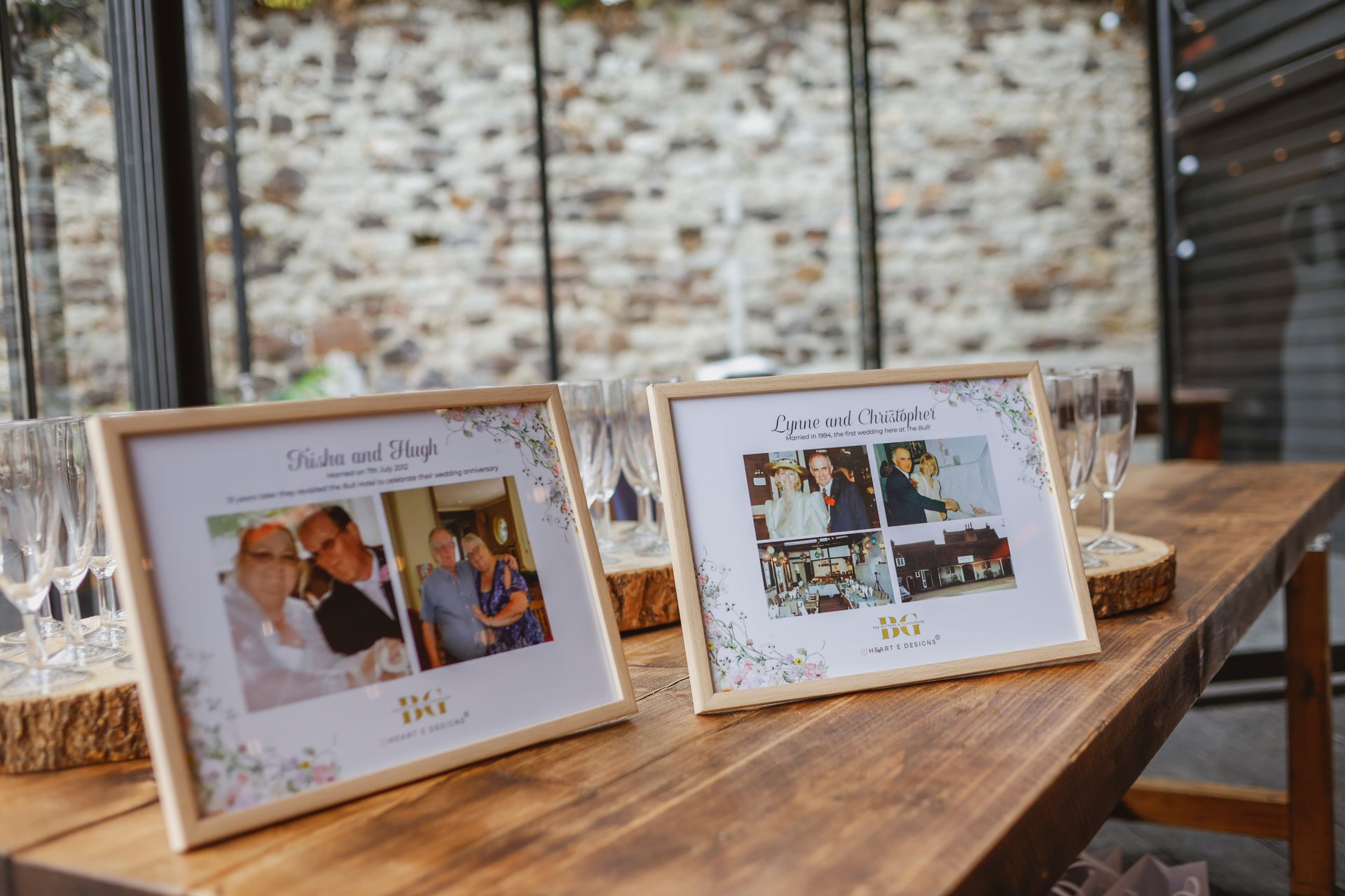 Two framed photo table cards on a wooden table at a wedding reception