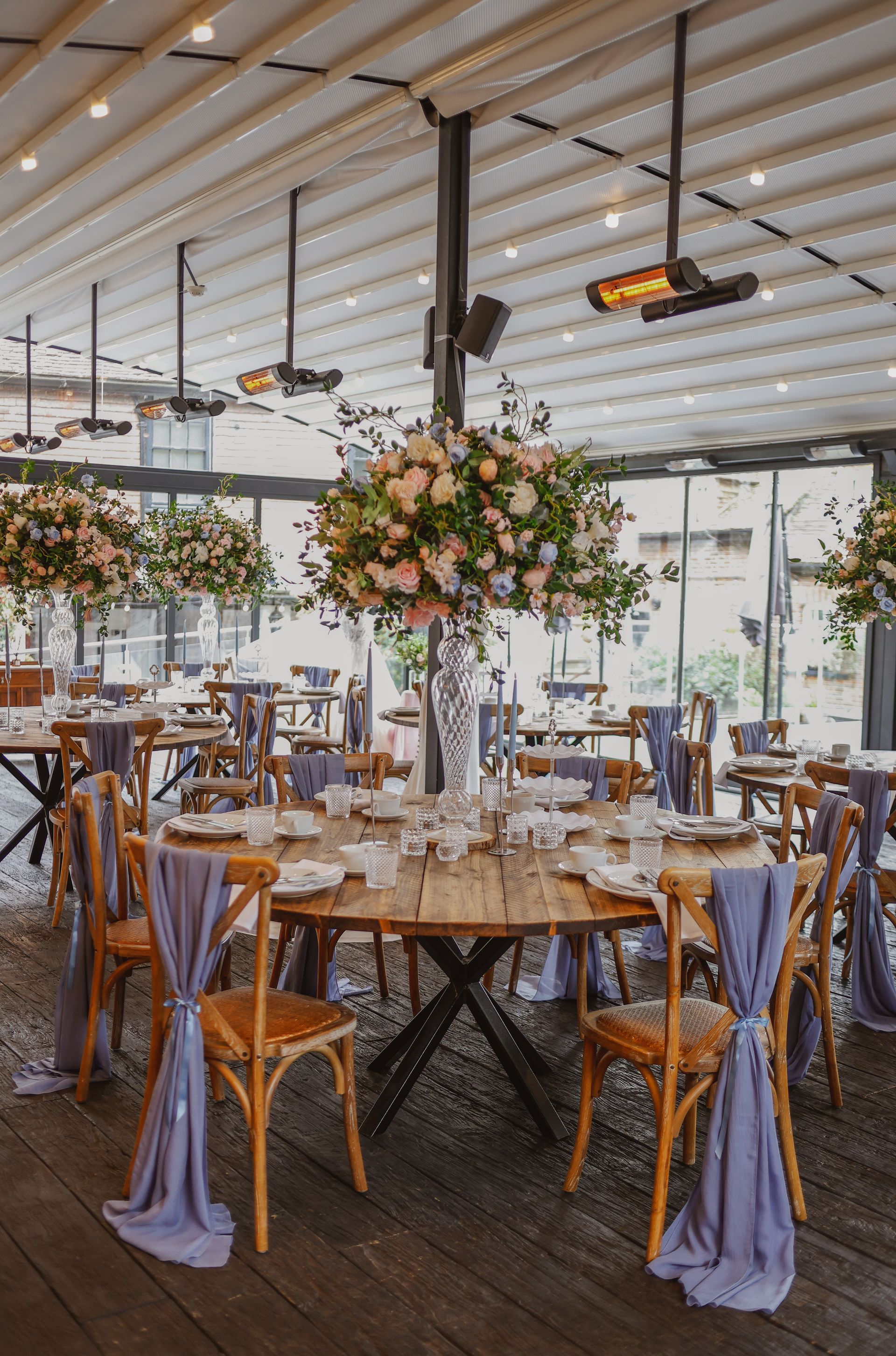 Elegant banquet table set beneath hanging floral centerpieces in a bright tented venue