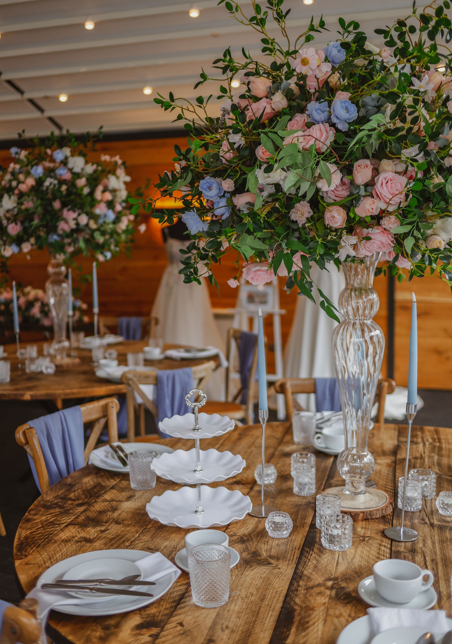 Elegant banquet table with gold runner, white plates, blue napkins, and pink-blue floral centerpieces