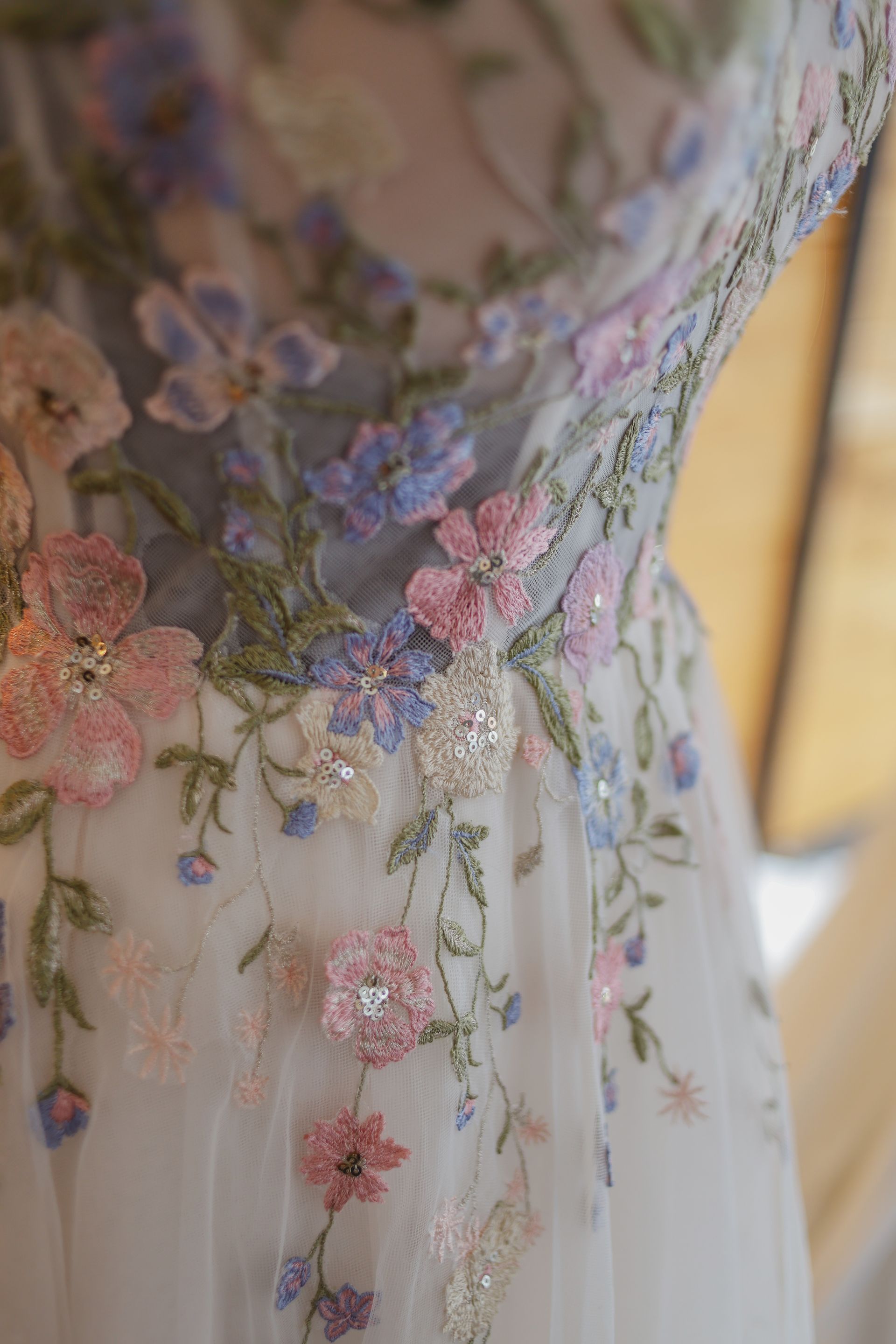 Sheer floral embroidered dress bodice in pastel pink, purple, and green on a mannequin