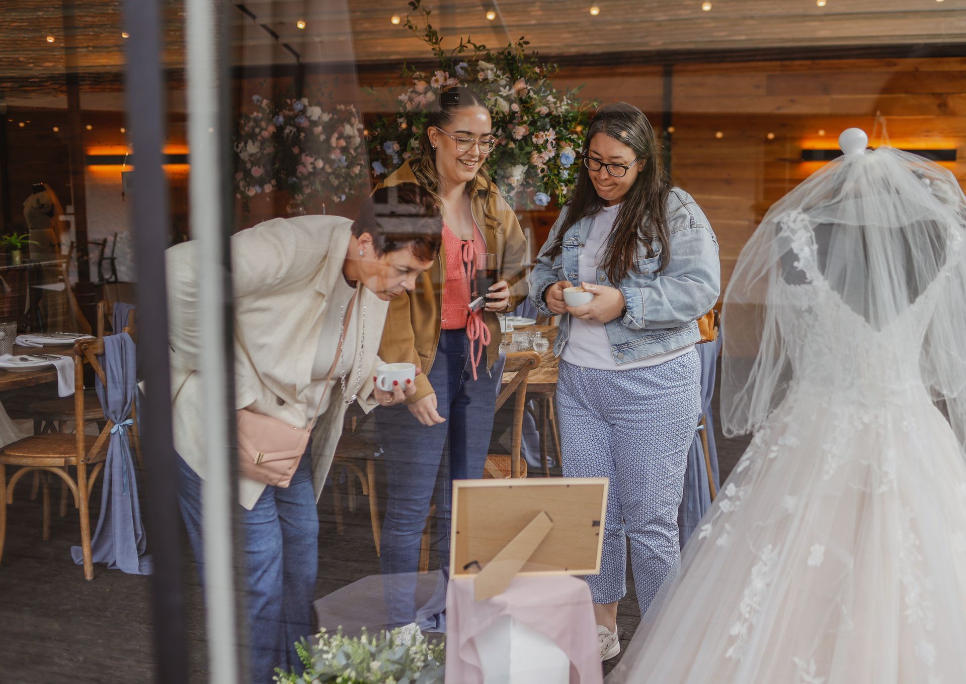 Guests chatting beside a bride in a veil at a wedding venue window display