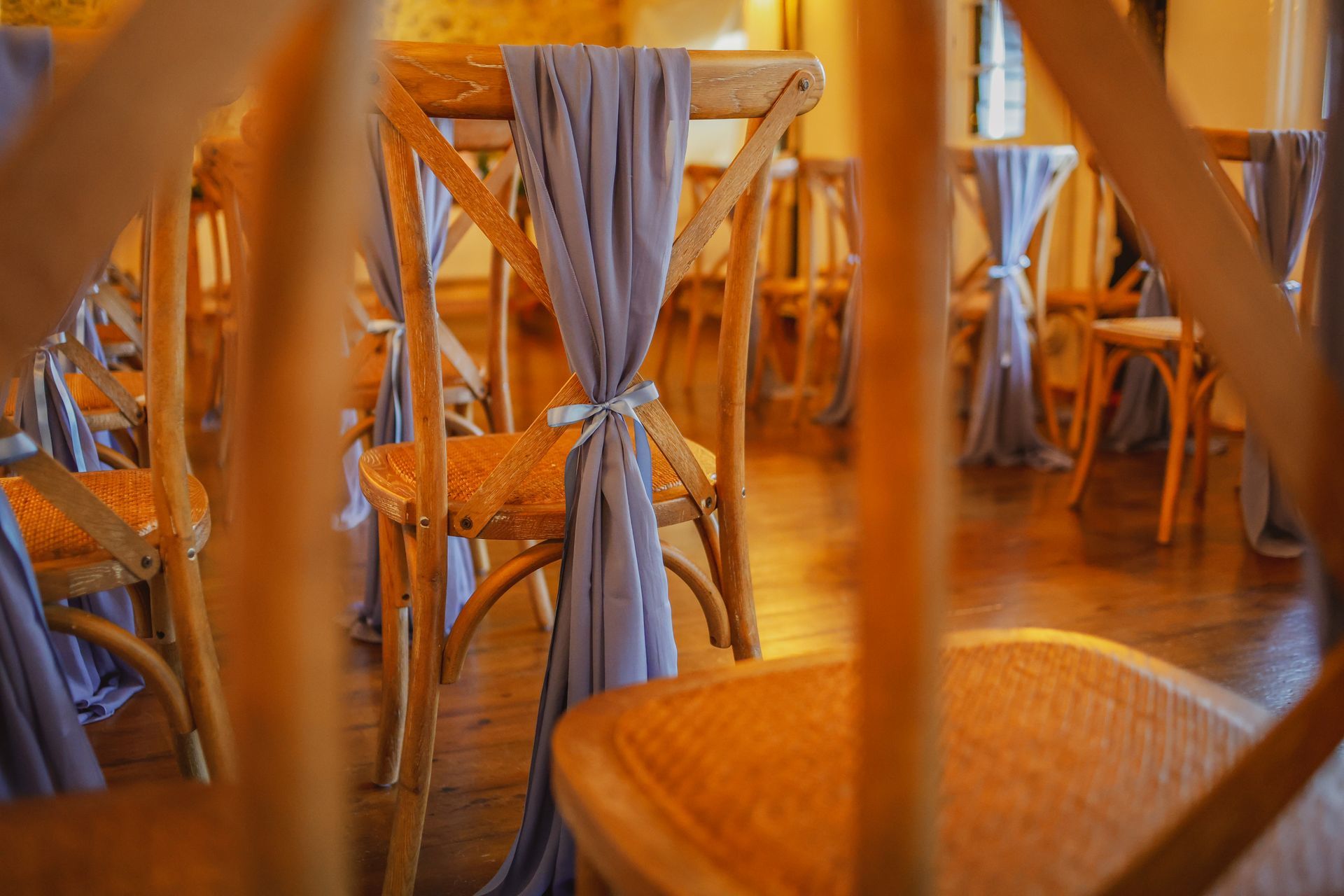 Wooden chairs tied with gray fabric in a warmly lit dining area
