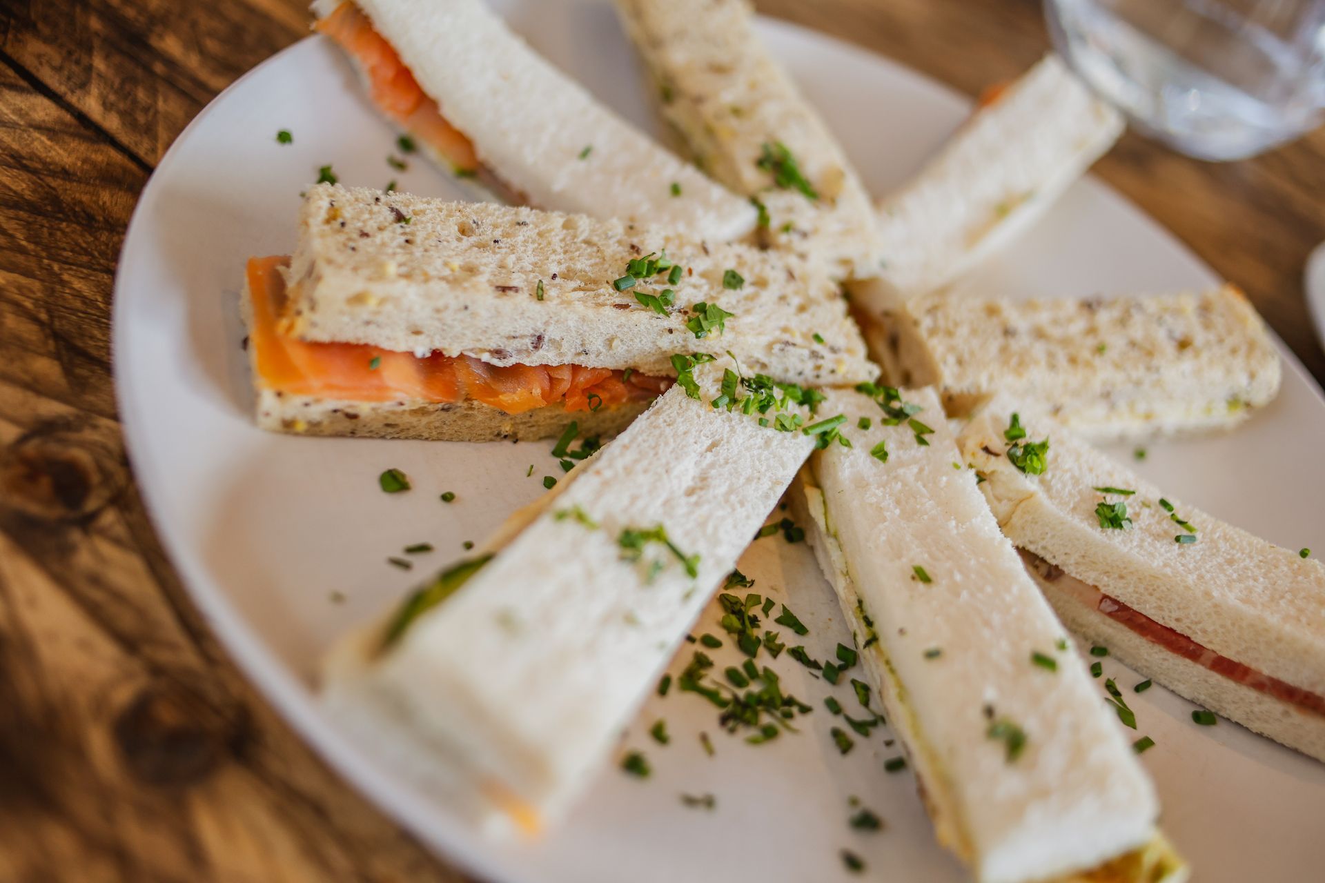 Club sandwich cut into triangular pieces on a white plate, garnished with herbs